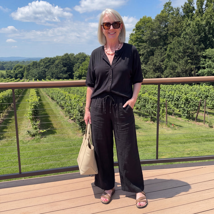 Woman in a black linen top and pants at a vineyard