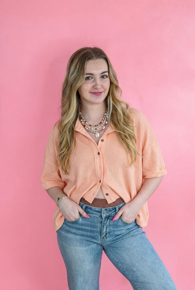 Woman in a peach button-up shirt and jeans